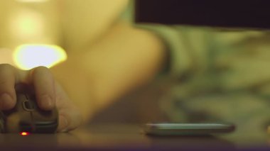 Bir adam evde bilgisayarla çalışıyor ve cep telefonundaki mesajlara cevap veriyor.