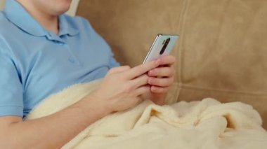 Kanepede elinde cep telefonu olan bir adam.