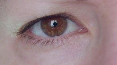 Kontakt lens takan bir kadının gözünün yakın çekimi.