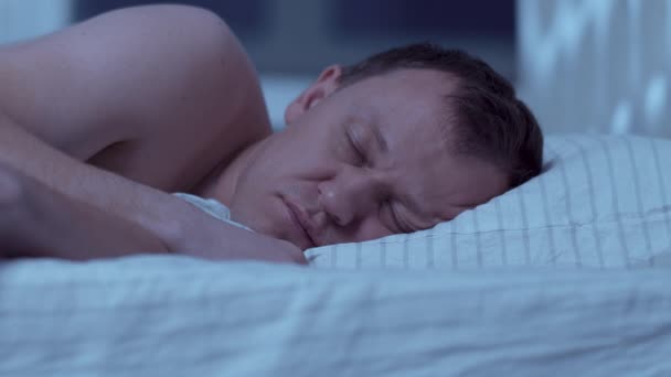 Ένας άντρας δεν μπορεί να κοιμηθεί από δυνατό θόρυβο και καλύπτει το κεφάλι του με ένα μαξιλάρι. — Αρχείο Βίντεο