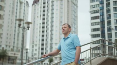 Genç adam merdivenlerde dikiliyor, arka planda gökdelenler, kamera hareketleri...