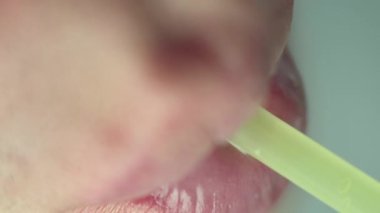 Plastik tüpten içen bir adamın dudakları, üst görüş, makro çekim.