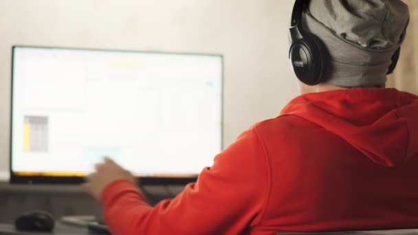 Een programmeur in een fabriek in een thuiskantoor in de avond zitten op een monitor scherm, ontwikkelt sites — Stockvideo