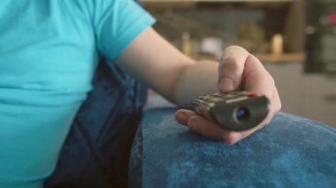 Uzaktan kumandalı bir adamın elinin düğmelere bastığı, kanalları değiştirdiği sandalyenin en kolu.