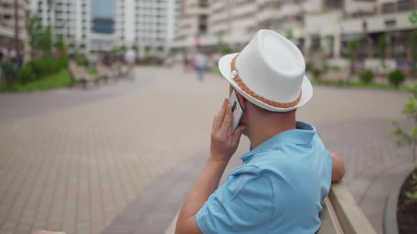 Burger praten op een mobiele telefoon tijdens het zitten op een bank, camera tracking, kopieerruimte — Stockvideo