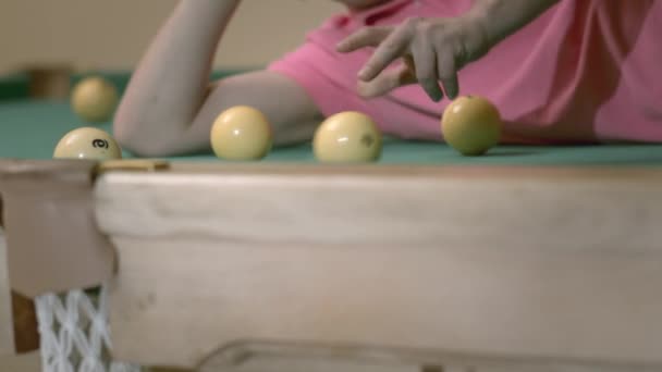 Az ember úgy szórakozik a biliárdasztalon, hogy egy biliárd labdát görget a zsebébe a kezével. — Stock videók