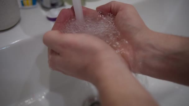 Man houdt zijn handpalmen onder een stroom van kraanwater, close-up — Stockvideo