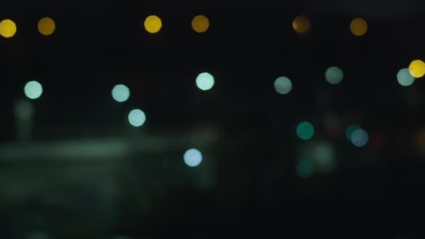 Luces de la ciudad nocturna en una ventana abierta, carretera con linternas, fondo borroso — Vídeos de Stock