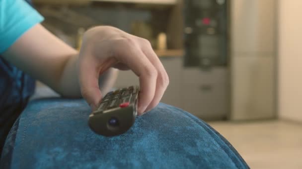 Hombre recoge un mando a distancia y conmuta canales, presiona botones, movimiento de la cámara — Vídeos de Stock