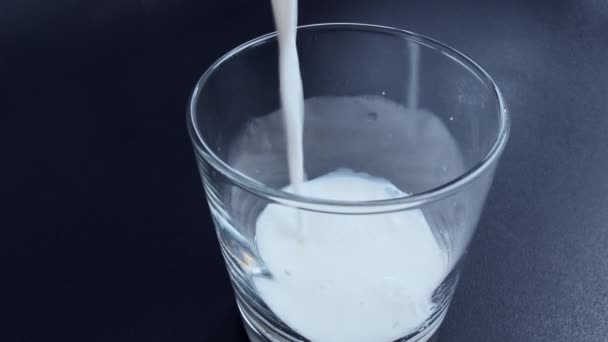 Fresh milk is poured into a glass, close-up, top view — 图库视频影像