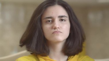 Doğrudan kameraya bakan esmer bir kızın portresi