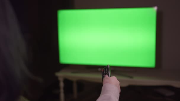 Girl switches channels by pressing the buttons on the remote control, sits at night at the TV, chromakey — Stock Video