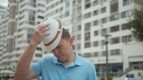 Portret van een aantrekkelijke man met hoed op de achtergrond van stadsgebouwen, camera tracking — Stockvideo