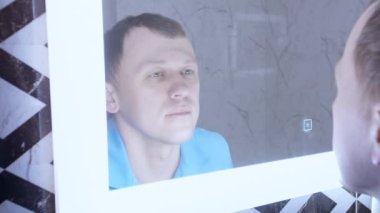 Adam aynadaki yansımasını ışık açıkken inceliyor.