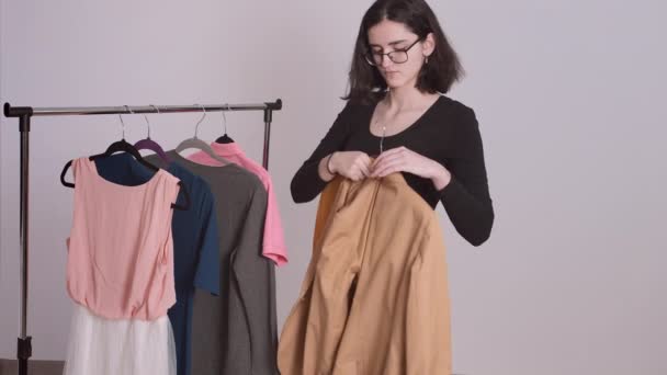 Chica, elige la ropa del estante, recoger la ropa para una reunión, se pone una chaqueta que le gustaba — Vídeos de Stock