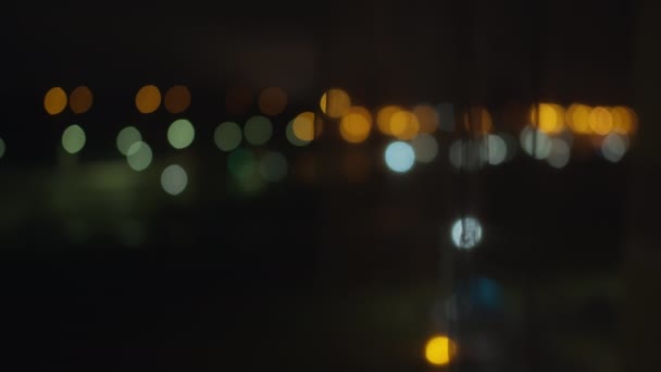 Luci sfocate colorate della città di notte dalla finestra aperta, dietro le tende di — Video Stock