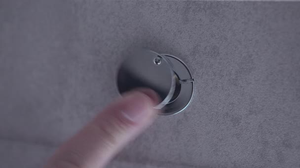A man moves a flap on the door peephole with his finger, looks outward — Stock Video