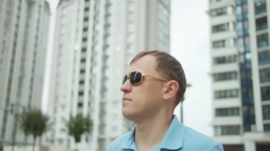 Şehir binalarının arka planında güneş gözlüklü genç çekici bir adamın portresi.