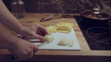 Bir adam akşam yemeği hazırlar, soğan ve peyniri parçalara ayırır.