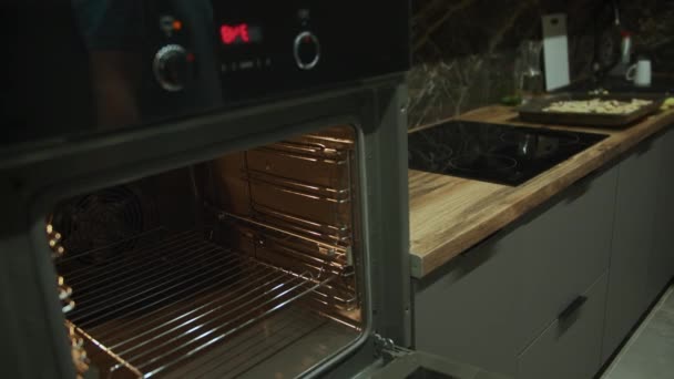 Un hombre abre la puerta del horno y pone una pizza grande en la sartén para cocinar, rastreo de la cámara, enfoque en rack — Vídeo de stock