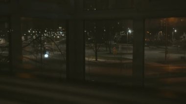 Gece ıssız bir cadde, pencerenin perdelerden geçişi, kamera takibi.
