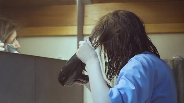 Girl in the bathroom dries her hair with a hairdryer after a shower — 图库视频影像