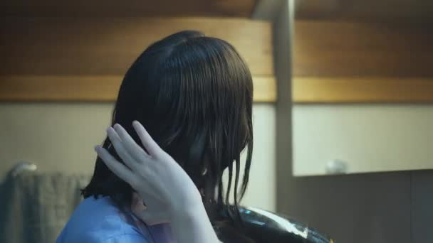 Mädchen trocknet nasses Haar nach der Dusche mit einem Haartrockner vor dem Spiegel — Stockvideo