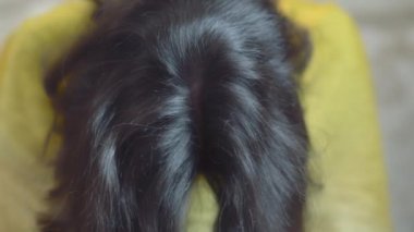 Esmer kız kameranın önünde başı aşağıda oturuyor.