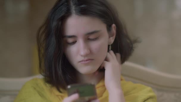 Sad teenage girl reading messages in a mobile phone — Stock Video