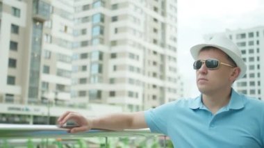 Metal korkulukların yanında duran bir adam cep telefonuyla konuşuyor.