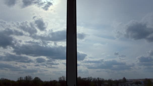 Gök gürültülü bulutlar yavaşça gökyüzünde süzülür, güneş ışınları, pencereden manzara — Stok video