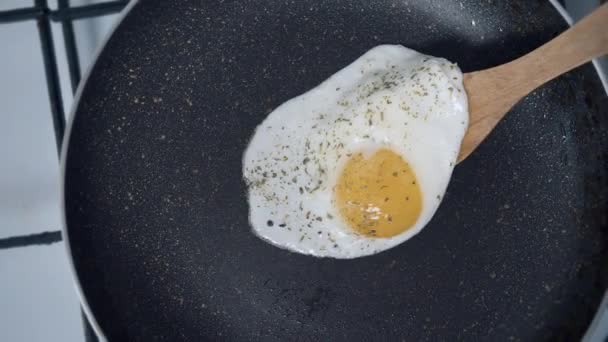 Яйцо со специями помещается на белую тарелку с деревянной лопаткой, крупным планом — стоковое видео
