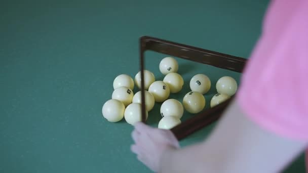 Играя в бильярд, человек в шарах собирает в треугольнике, следит за камерой — стоковое видео