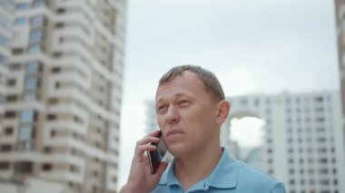 Çekici bir genç adam telefonda konuşuyor, caddede duruyor.