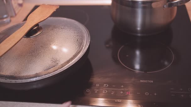 Жінка розігріває їжу на сковороді, перемішуючи її дерев'яним шпателем — стокове відео