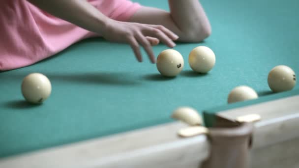 Um homem deitado em uma mesa de bilhar joga com bolas de bilhar, rola-los em um bolso, close-up — Vídeo de Stock