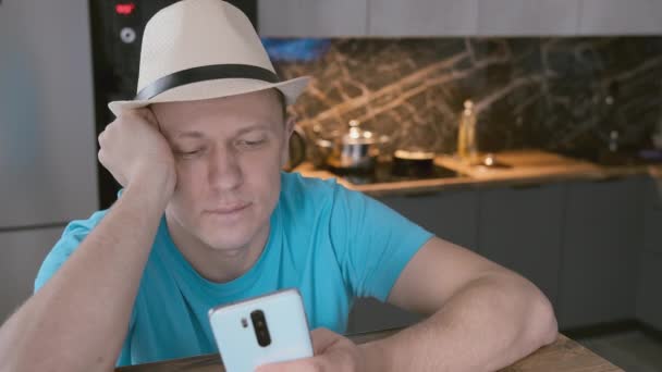 Hombre de sombrero blanco se sienta en la mesa utiliza el teléfono móvil — Vídeo de stock