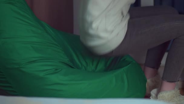 Девушка вечером в своей комнате садится отдыхать на бобовый мешок бросая руки за голову, понятие отдыха — стоковое видео