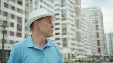 Şapkalı çekici bir adam onu çıkartıyor, şehrin caddesinde duruyor.