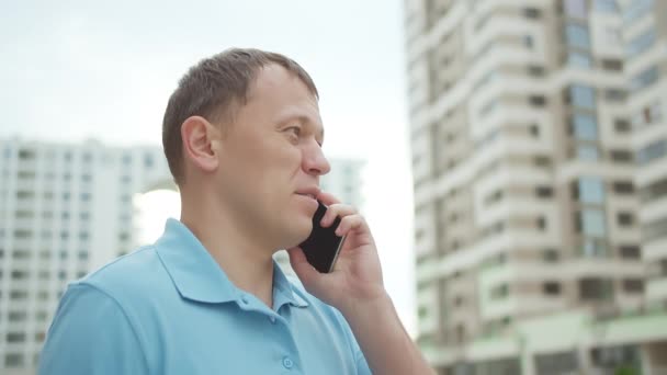 Portret mężczyzny rozmawiającego przez telefon komórkowy na tle wieżowców — Wideo stockowe