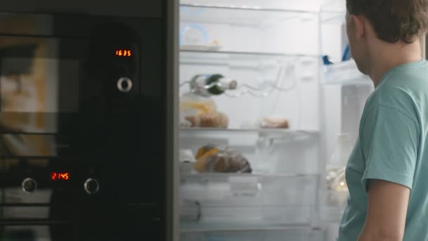 若い男が冷蔵庫を開けてビールを１本 — ストック動画