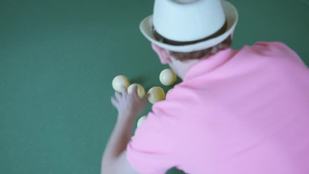 Joueur de billard, homme en t-shirt rose et chapeau recueille des balles dans un triangle — Video