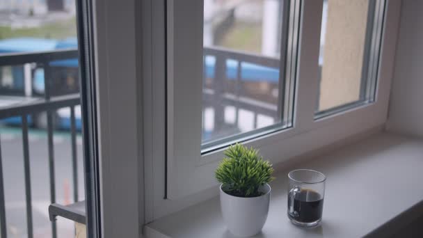 Une tasse de café est sur le rebord de la fenêtre, à l'extérieur de la fenêtre la circulation et les gens — Video