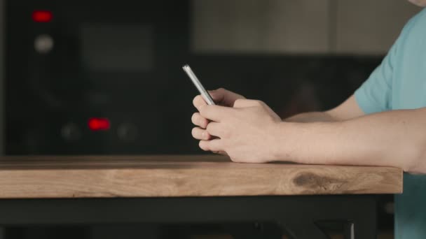 Mans händer håller en telefon på ett träbord — Stockvideo