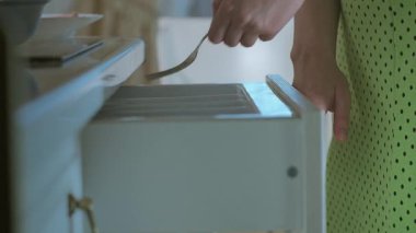 Elbiseli bir kız bir çatal ve bir tabak yemek alıp masaya oturur, yemek yer, odaklanır ve evde yer.