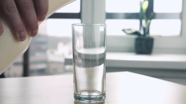 Adam sütü sürahide masaya döker.