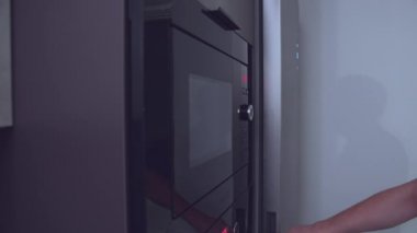 Adam akşam yemeğini ısıtır, buzdolabından bir tabak yemek çıkarır ve çabucak ısıtmak için mikrodalgaya koyar.