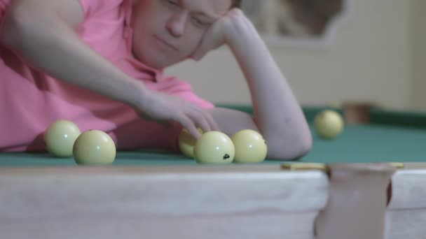 Young man playing with billiard balls while lying on billiard table — Stock Video