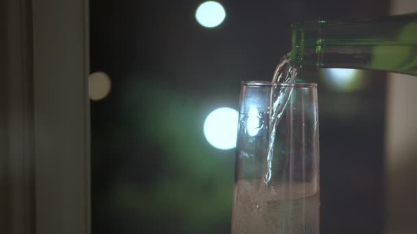 Champagne wordt gegoten in een glas uit een fles, nachtlampjes — Stockvideo