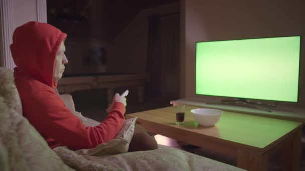 L'uomo nel cofano guarda la TV, si siede sul divano a casa la sera, cromakey — Video Stock